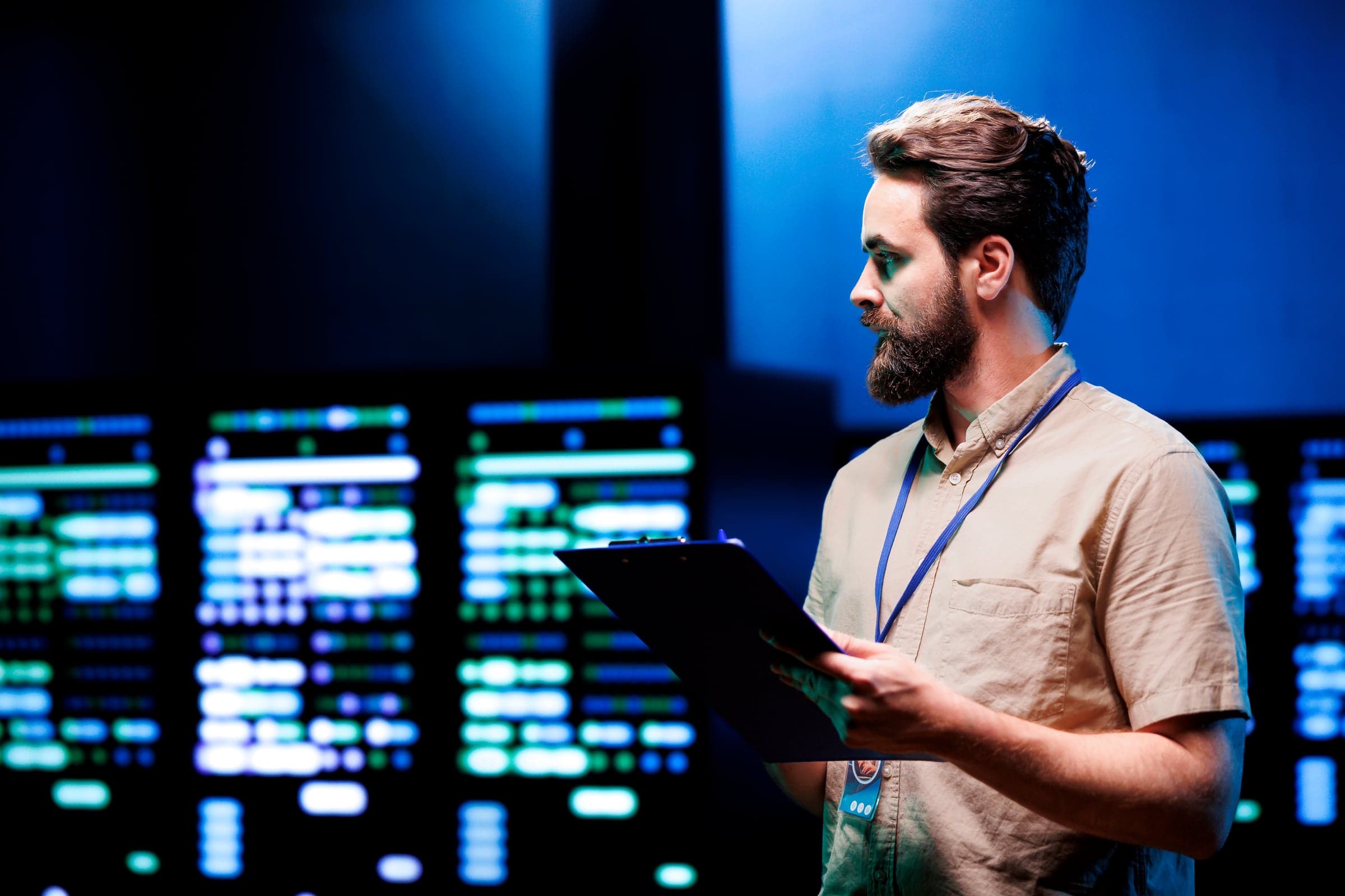 IT-Techniker mit Klemmbrett vor Serverschränken mit Statusanzeigen